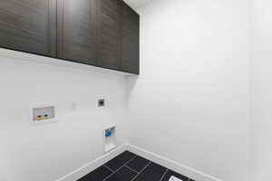 Laundry room with cabinet space, electric dryer hookup, washer hookup, and dark tile patterned flooring