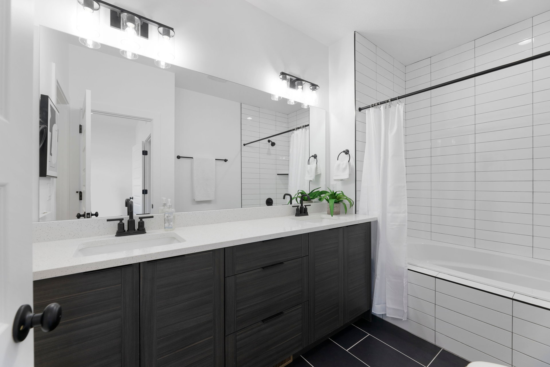 Full bath featuring vanity, tiled shower / bath, and dark tile patterned flooring