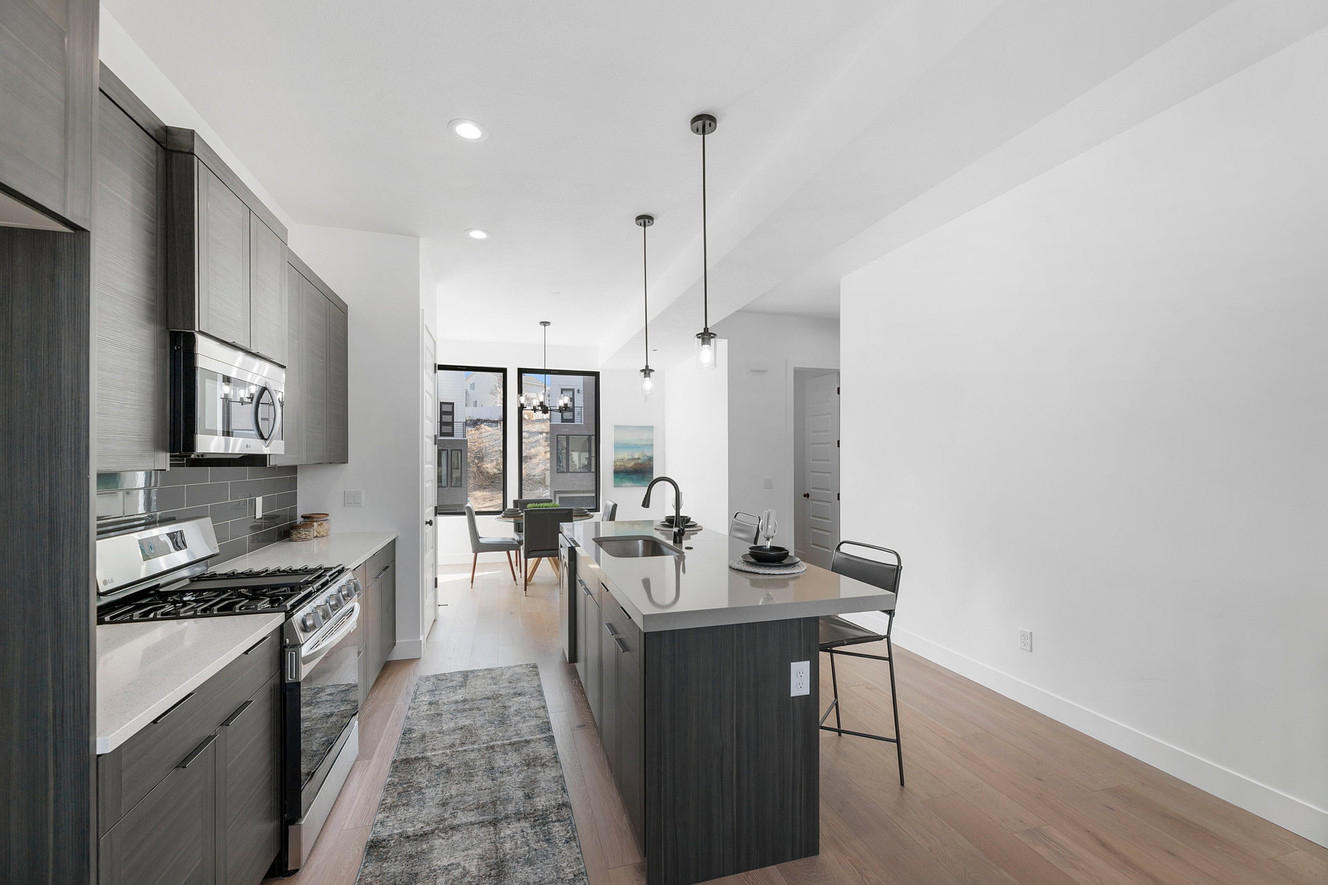 Kitchen featuring stainless steel appliances, a kitchen breakfast bar, modern cabinets, a center island with sink, and backsplash