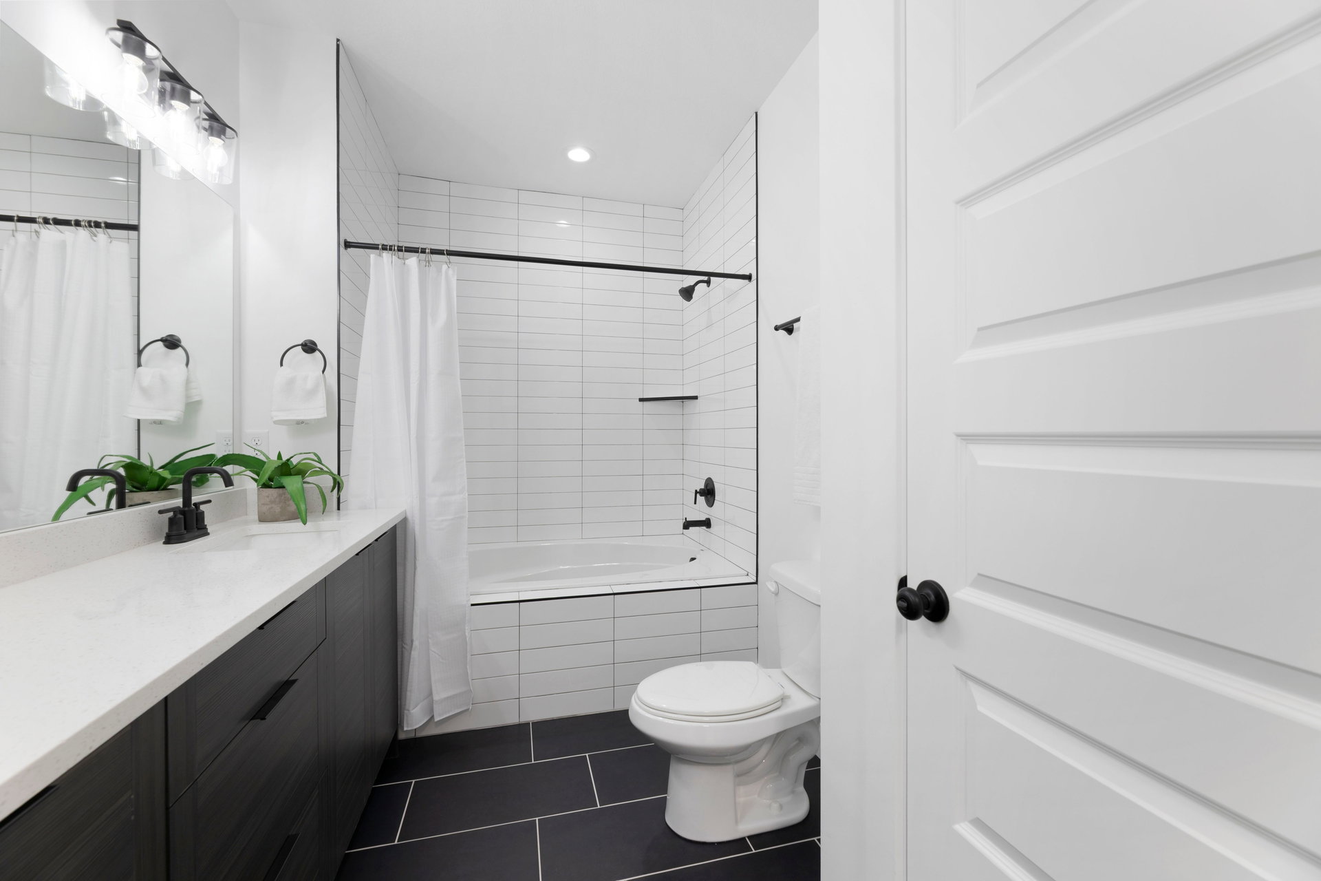 Full bathroom featuring vanity, tiled shower / bath combo, dark tile patterned floors, and recessed lighting
