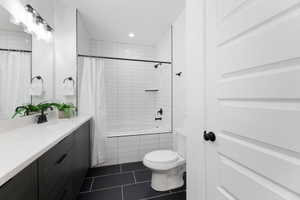 Full bathroom featuring vanity, tiled shower / bath combo, dark tile patterned floors, and recessed lighting