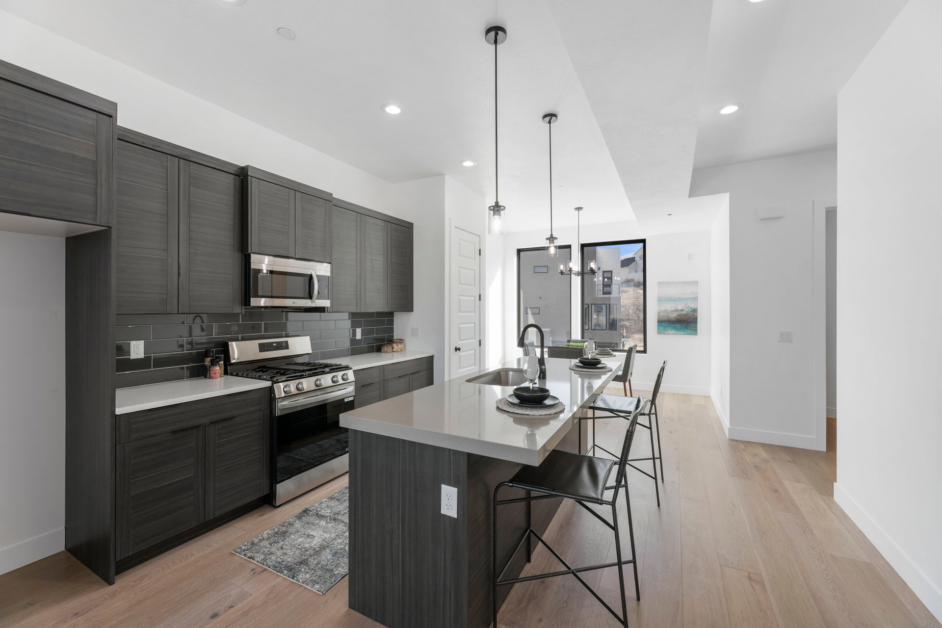 Kitchen with stainless steel appliances, a breakfast bar area, a center island with sink, light wood finished floors, and modern cabinets