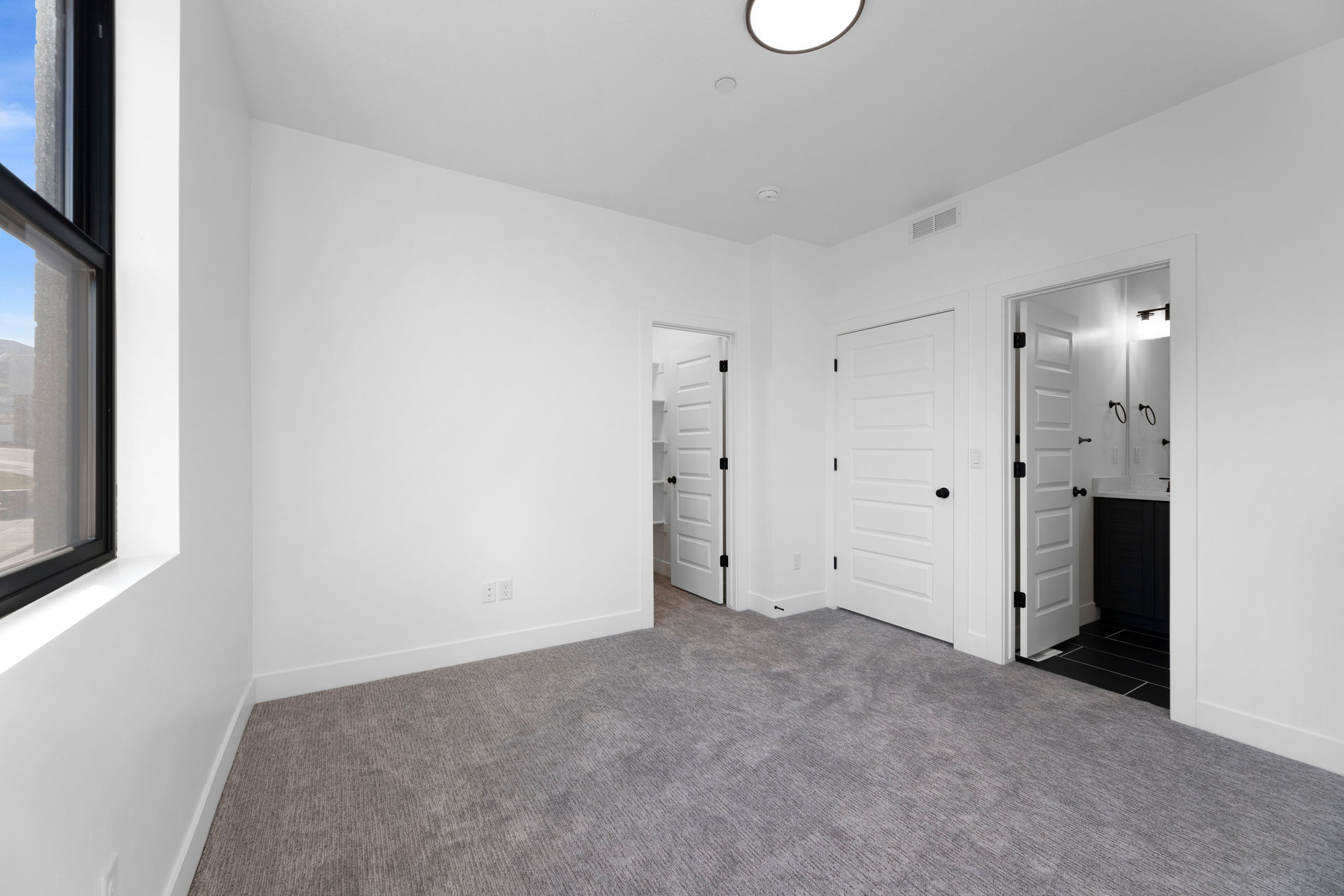 Unfurnished bedroom with dark colored carpet, a closet, and ensuite bath