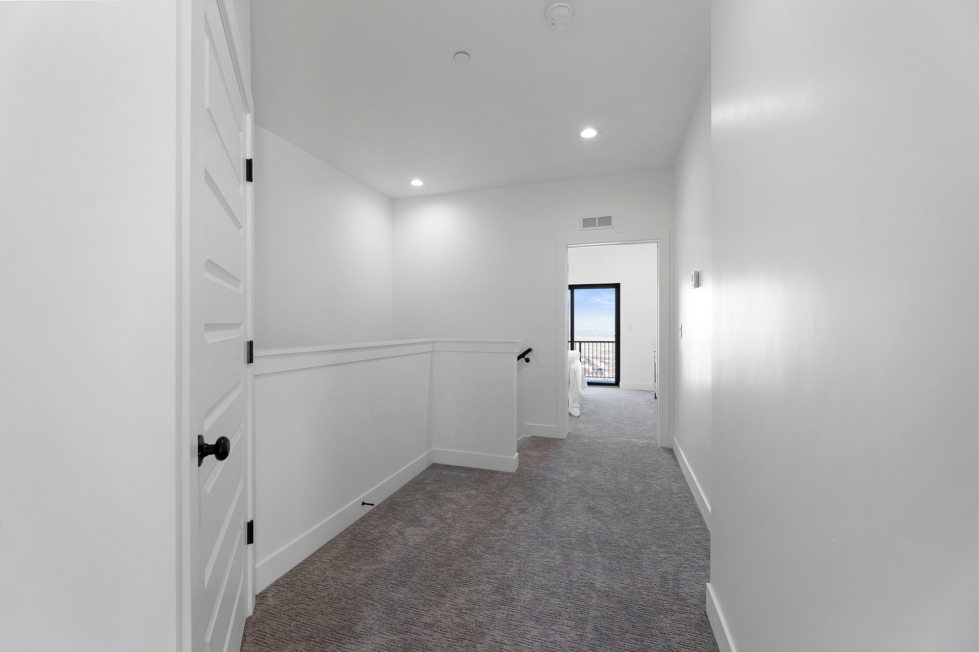 Hallway with dark colored carpet and recessed lighting