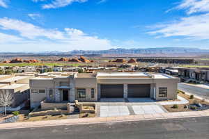 View of front facade with stucco siding, stone siding, a residential view, concrete driveway, and a mountain view
