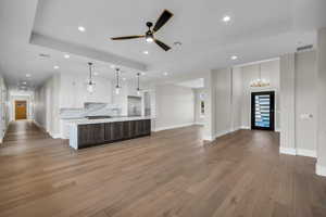 Kitchen with open floor plan, a spacious island, a ceiling fan, dark wood-style floors, and dual tone cabinetry