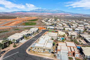 Aerial view of property and surrounding area featuring mountains and nearby suburban area