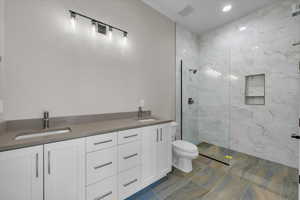 Bathroom featuring double vanity, a marble finish shower, and recessed lighting