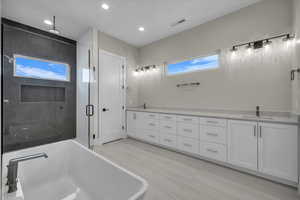 Bathroom with double vanity, a freestanding tub, a stall shower, and recessed lighting