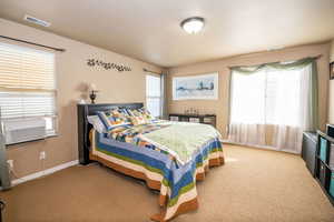 Carpeted bedroom with baseboards and cooling unit
