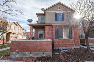 Rear view of property featuring stucco siding and brick siding