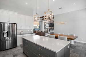 Kitchen with stainless steel refrigerator with ice dispenser, dual tone cabinets, tasteful backsplash, a center island, and a chandelier