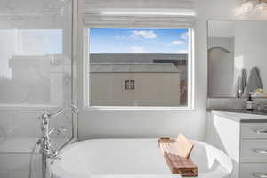 Full bathroom with a freestanding tub, vanity, and decorative backsplash