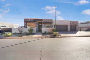 View of front facade featuring stone siding, driveway, a garage, and stucco siding