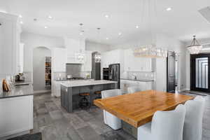 Kitchen with a center island, a kitchen bar, decorative backsplash, arched walkways, and hanging lights