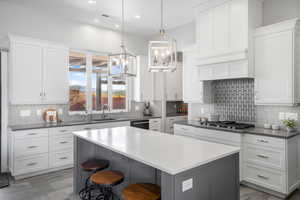 Two tone kitchen featuring a kitchen breakfast bar, a center island, dual tone cabinetry, suspended lighting, and black dishwasher