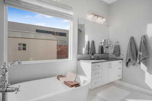 Bathroom featuring vanity, a freestanding bath, and light marble finish flooring