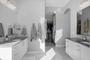 Full bathroom featuring a spacious closet and two vanities