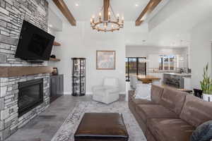 Living area with beam ceiling, a fireplace, and a chandelier