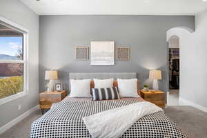 Carpeted bedroom featuring arched walkways and a walk in closet
