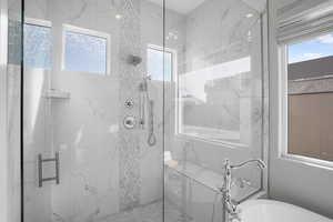 Bathroom featuring a marble finish shower and a soaking tub