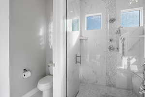 Full bathroom featuring a marble finish shower and healthy amount of natural light