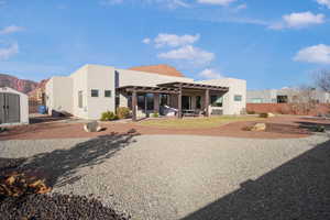 Rear view of house with a patio area, stucco siding, a storage shed, and a mountain view