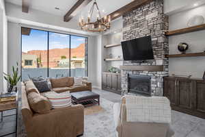 Living room with beam ceiling, hanging lights, and a stone fireplace