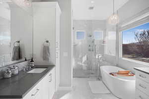 Full bathroom featuring vanity, a freestanding bath, a marble finish shower, hanging lights, and light marble finish flooring