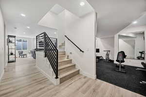Staircase with wood finished floors and recessed lighting