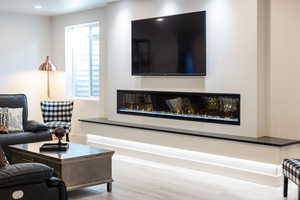 Living area featuring wood finished floors and a glass covered fireplace