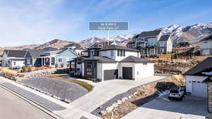 View of front of property with a mountain view, a residential view, concrete driveway, and an attached garage