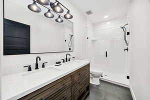 Bathroom with a stall shower, double vanity, recessed lighting, and dark tile patterned floors