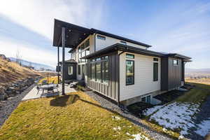 View of side of home featuring a patio area, a lawn, a balcony, and a mountain view