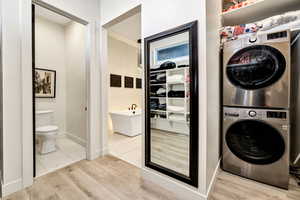 Laundry area featuring stacked washing machine and dryer and light wood finished floors