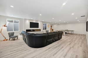 Living room featuring light wood finished floors, recessed lighting, and a glass covered fireplace