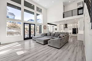 Living room featuring recessed lighting, french doors, a high ceiling, and light wood-type flooring