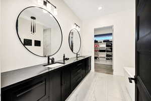 Bathroom with a walk in closet, double vanity, and recessed lighting