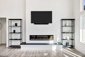 Unfurnished living room with a glass covered fireplace and light wood finished floors