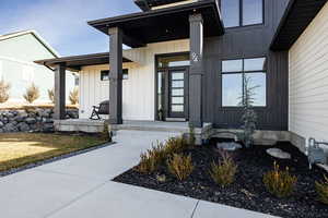 View of exterior entry featuring board and batten siding and covered porch