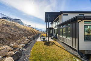 View of property exterior with a patio, board and batten siding, and a balcony