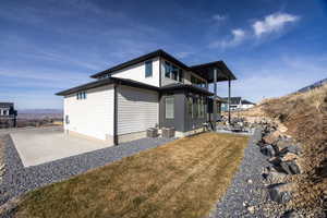 View of property exterior with a patio, a balcony, and a lawn