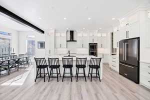 Kitchen featuring glass fronted cabinets, a kitchen breakfast bar, a spacious island, high end fridge, and white cabinets
