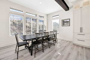 Dining room with beamed ceiling, light wood-style flooring, and recessed lighting