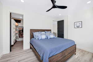 Bedroom featuring a spacious closet, light wood-style flooring, ceiling fan, and recessed lighting