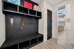 Mudroom featuring light wood-style flooring and baseboards