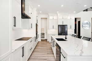 Kitchen featuring light stone counters, recessed lighting, white cabinets, black appliances, and light wood-type flooring