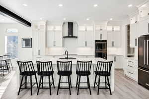 Kitchen with a large island, black appliances, recessed lighting, glass fronted cabinets, and white cabinets