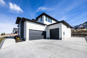 View of property exterior with concrete driveway and an attached garage