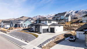 View of front of property with a mountain view, a residential view, concrete driveway, and a garage